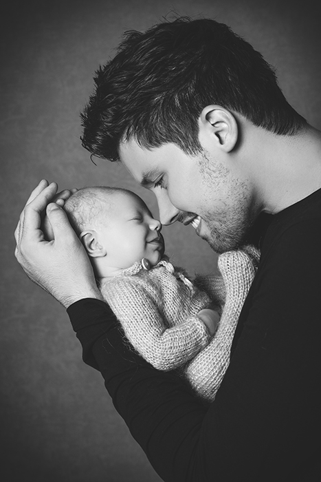 Auf diesem Foto hält ein Papa sein Baby und gibt ihm ein Nasenküsschen